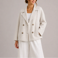 Women's double-breasted blazer in cream with notched lapels and cropped length, worn over white trousers