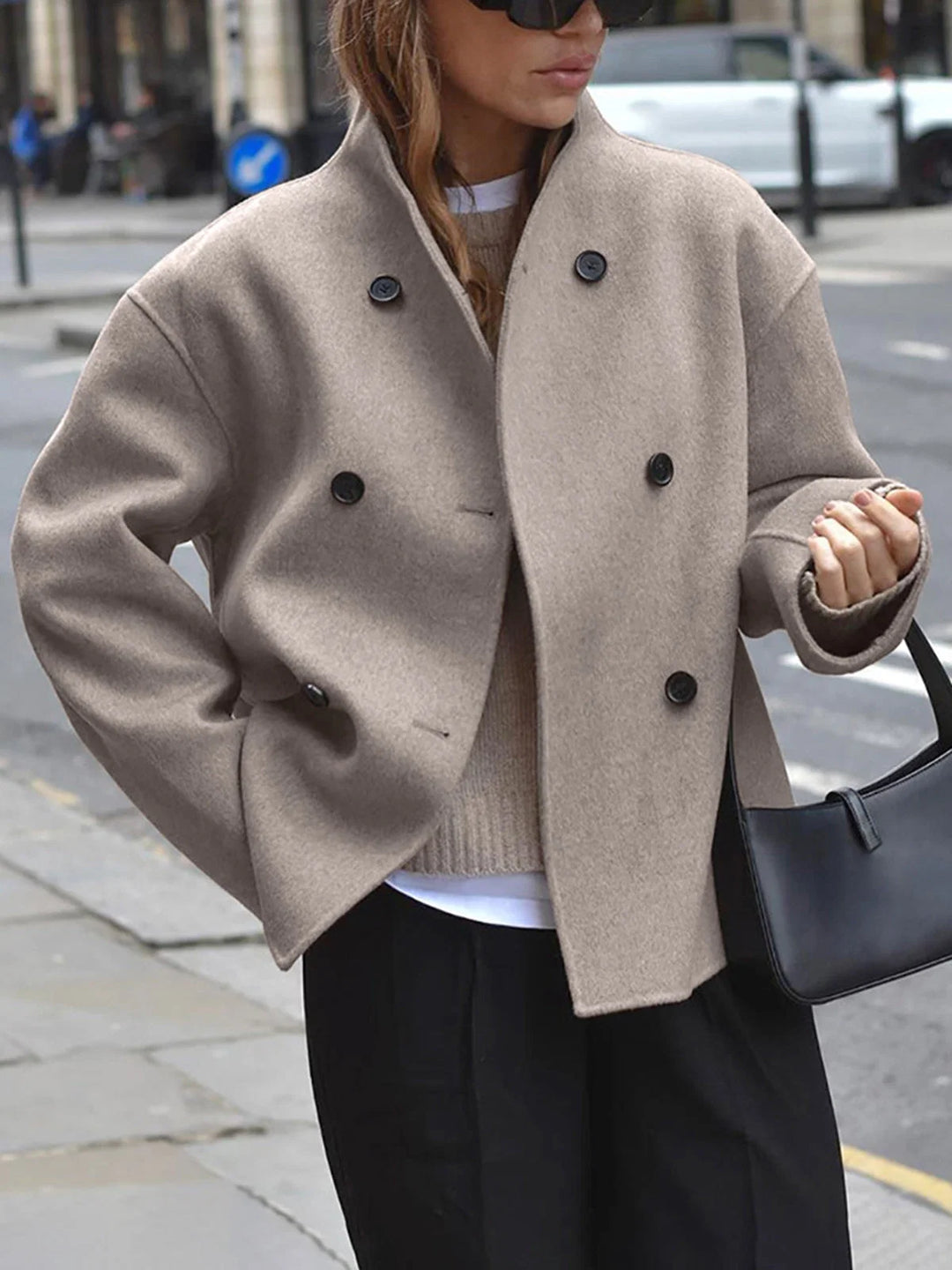 Women's double breasted pea coat in taupe with stand collar and relaxed fit worn outdoors