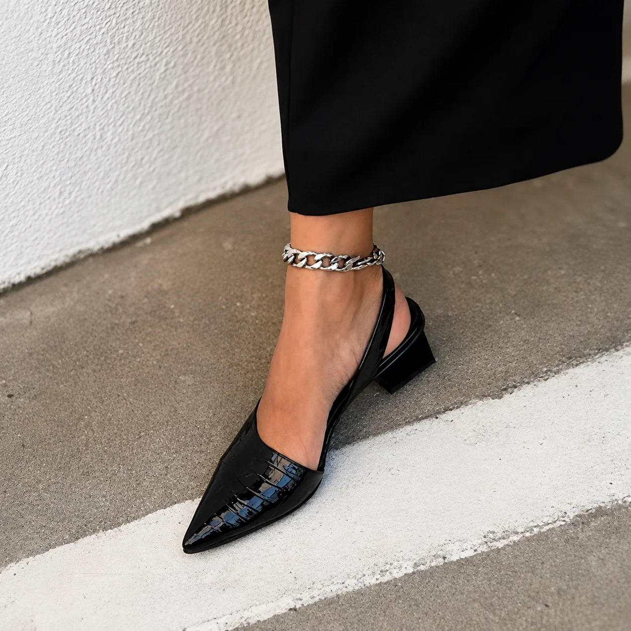 Detail shot of crocodile-embossed upper and elastic slingback feature on women's block heel pumps