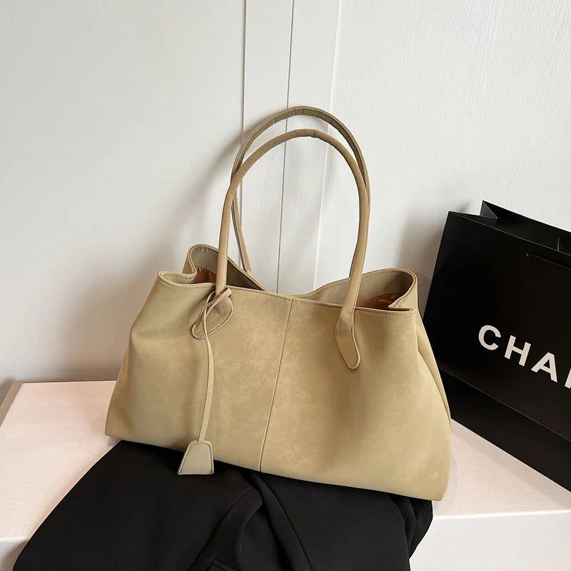 Close-up of tote bag handle attachment and detachable charm accent detail