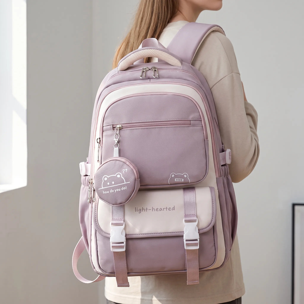School backpack with multiple compartments in lilac and cream colourway worn on shoulders showing front zip pockets