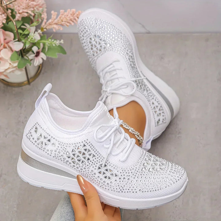 Women's embellished trainers with rhinestone detailing and lace-up closure on grey surface