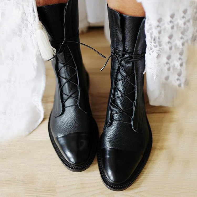 Women's black lace-up ankle boots with textured finish and glossy toe cap on wooden floor
