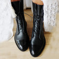 Women's black lace-up ankle boots with textured finish and glossy toe cap on wooden floor