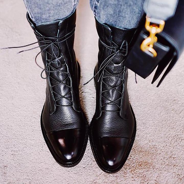 Women's lace-up ankle boots paired with white lace dress on wooden surface