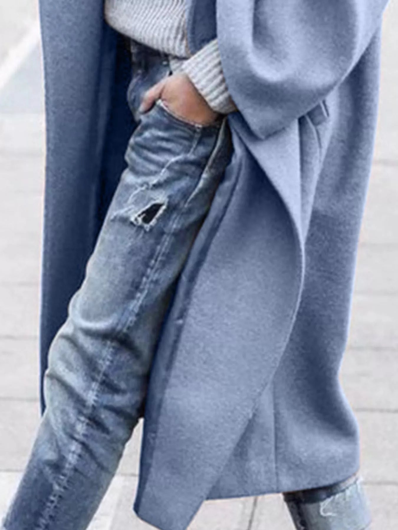 Lifestyle shot of women's oversized long coat in neutral taupe paired with casual denim and jumper