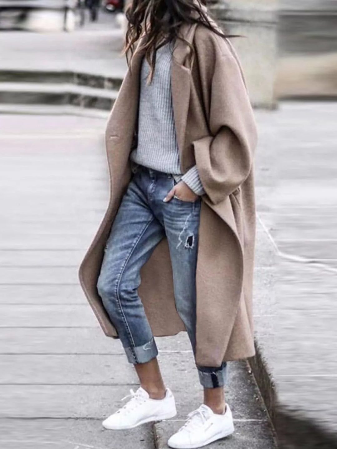 Close-up of women's oversized long coat featuring structured fabric, notch lapels and wide sleeve detail