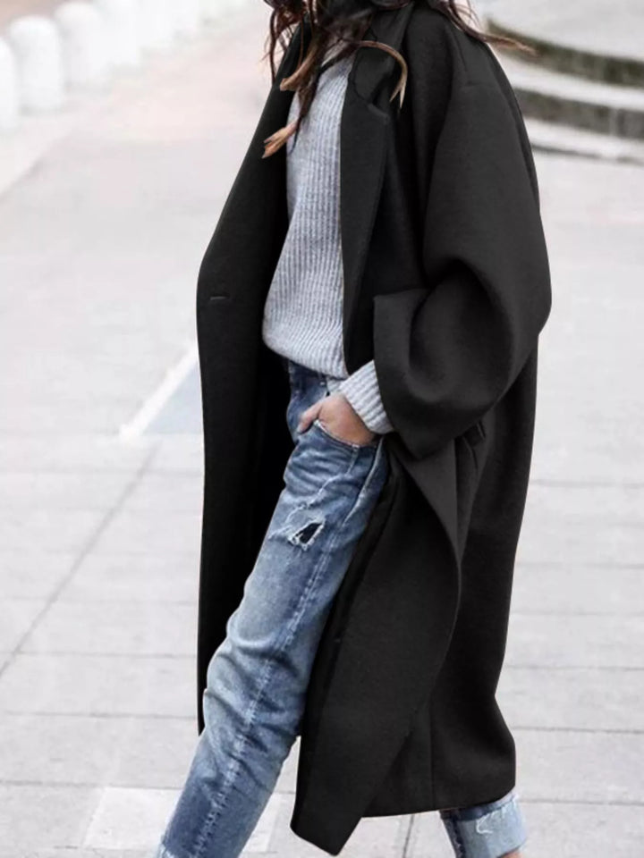 Women's oversized long coat in taupe layered over grey jumper and distressed jeans for casual styling