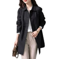 Black short trench coat for women showing structured silhouette and hip length cut with flap pockets