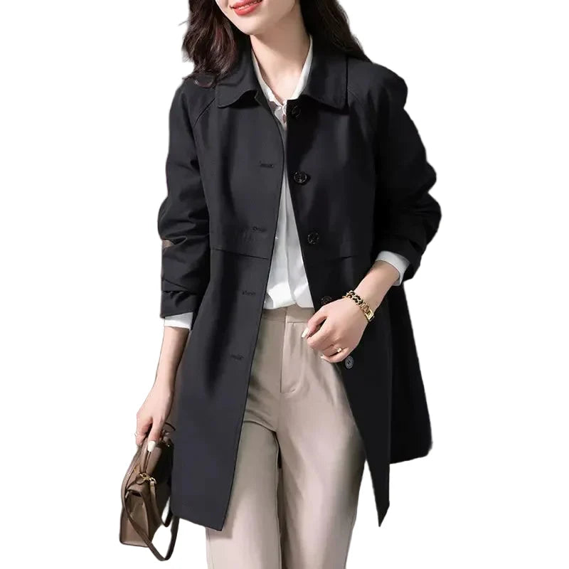 Black short trench coat for women showing structured silhouette and hip length cut with flap pockets
