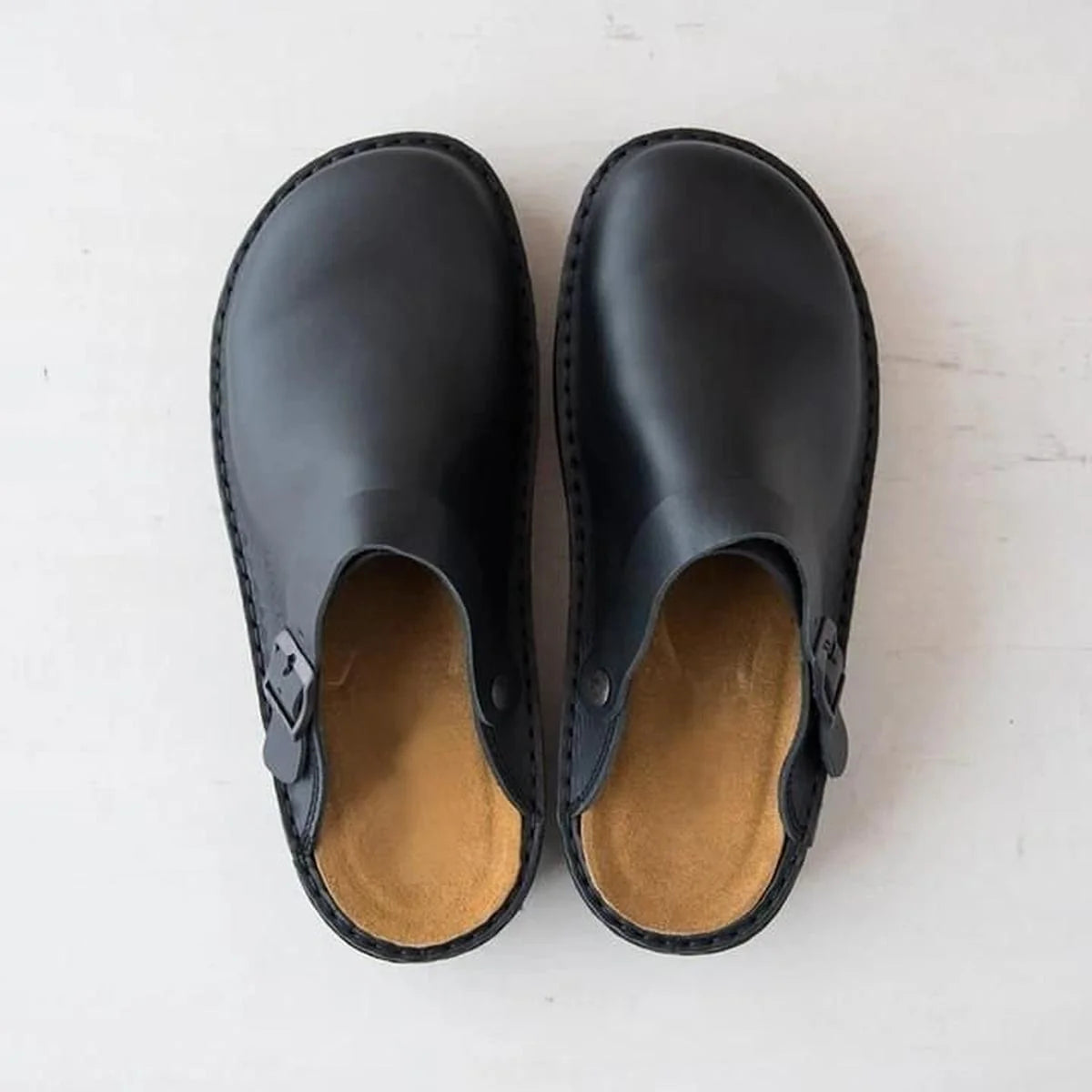 Overhead view of men's arch support mules in black with contoured footbed and adjustable side buckle