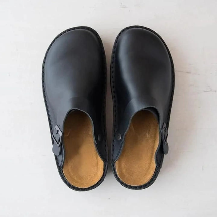 Overhead view of men's arch support mules in black with contoured footbed and adjustable side buckle