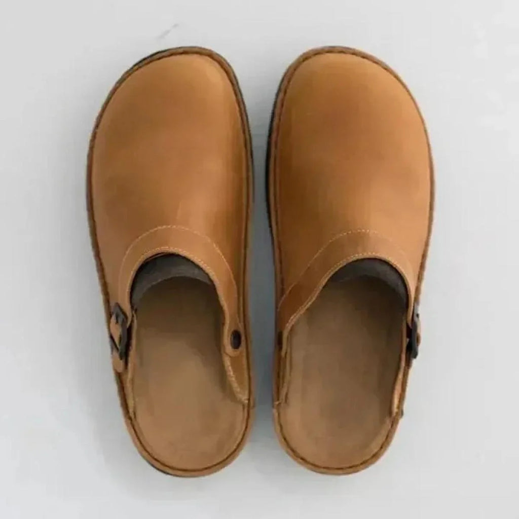 Side profile of men's slip-on mules showing adjustable buckle closure and textured rubber outsole