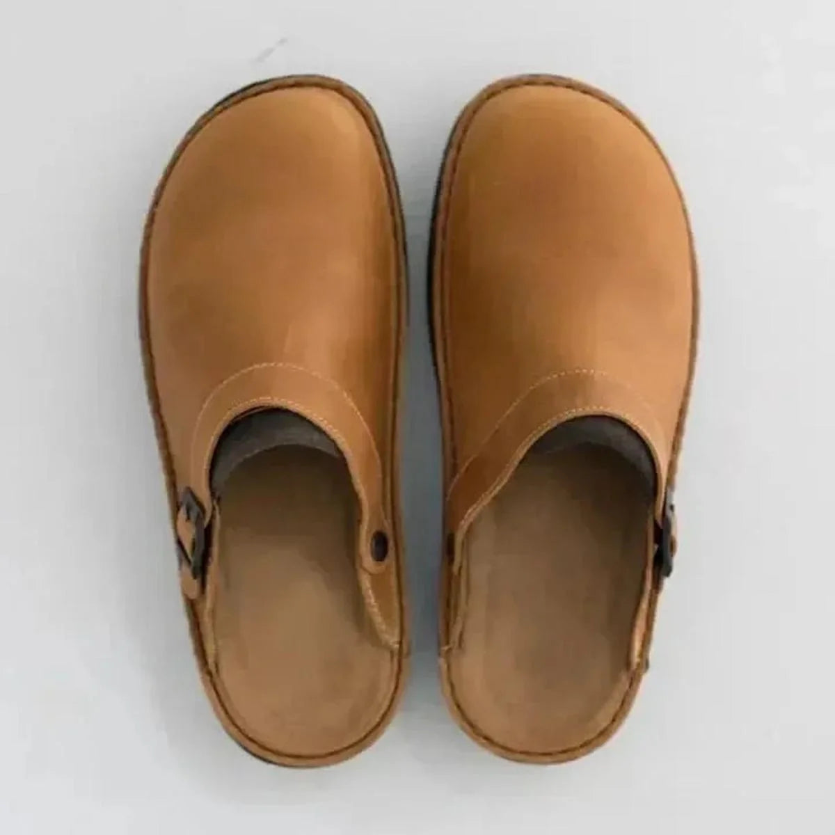 Side profile of men's slip-on mules showing adjustable buckle closure and textured rubber outsole