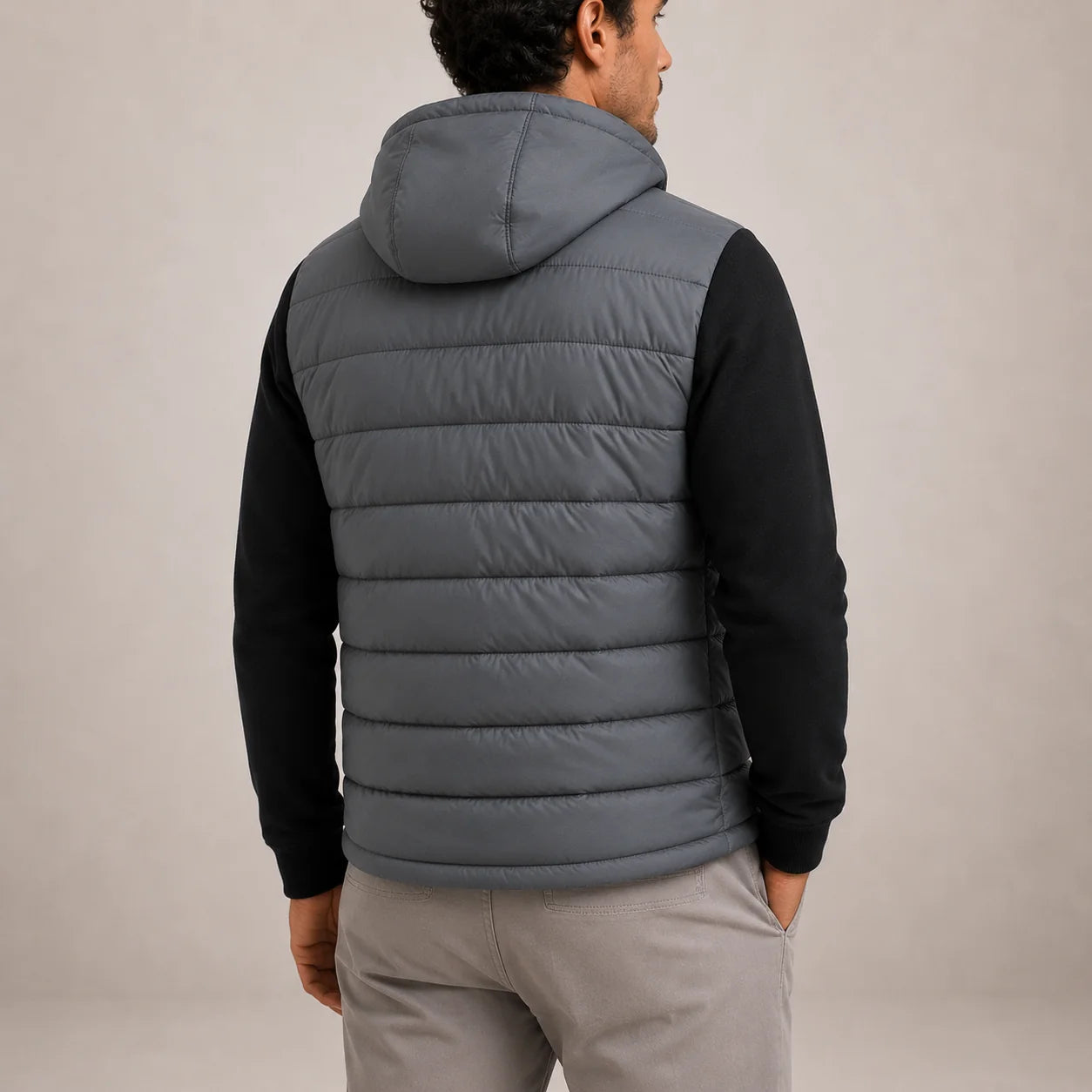Men's black puffer jacket with full-zip front worn over grey shirt and chinos