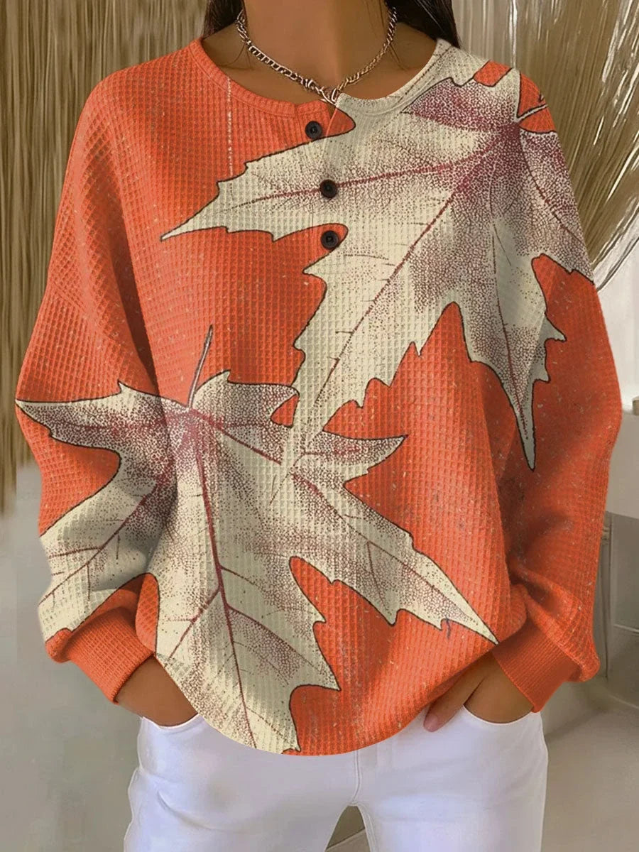 Women's peach leaf print long sleeve blouse with V-neckline and relaxed fit, styled with white trousers