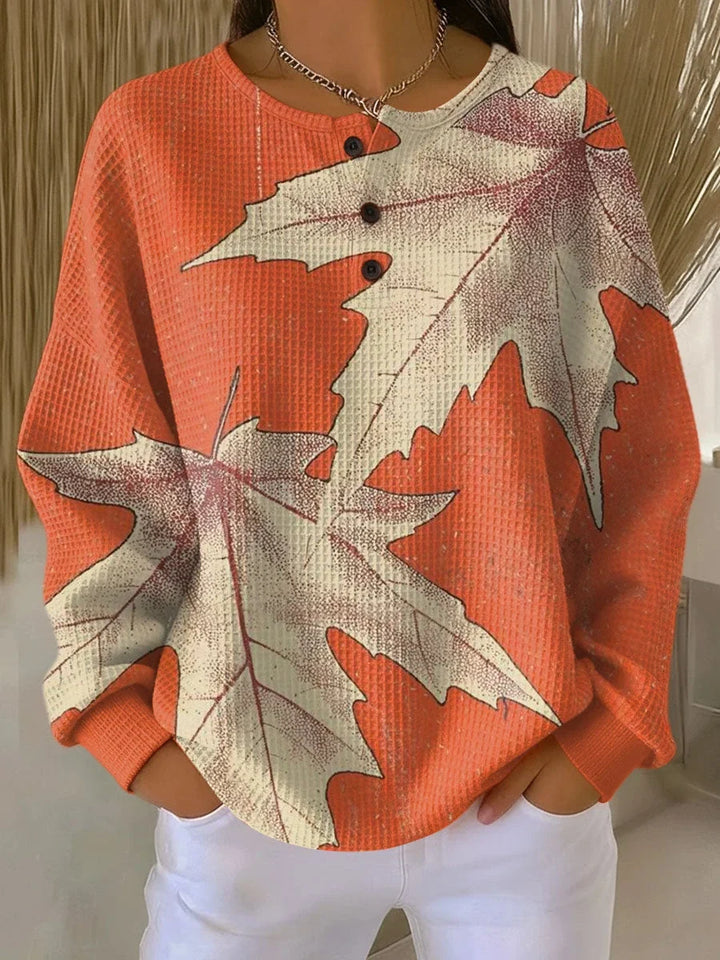 Women's peach leaf print long sleeve blouse with V-neckline and relaxed fit, styled with white trousers