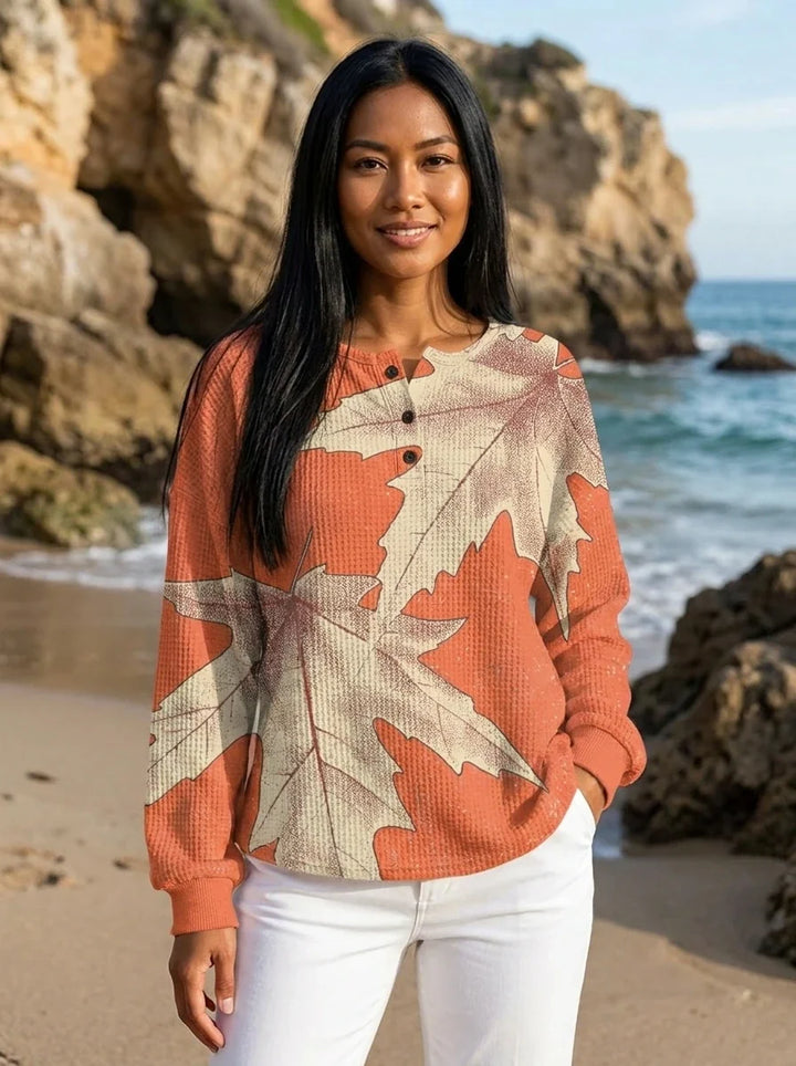 Close-up of oversized leaf print detail on peach long sleeve blouse with smooth fabric texture