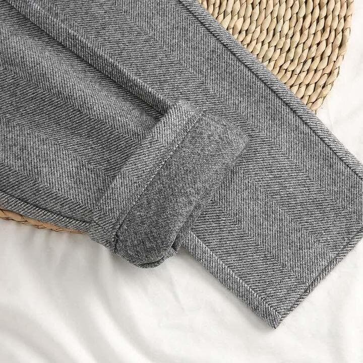 Side view of men's herringbone trousers with pleated front and relaxed leg drape