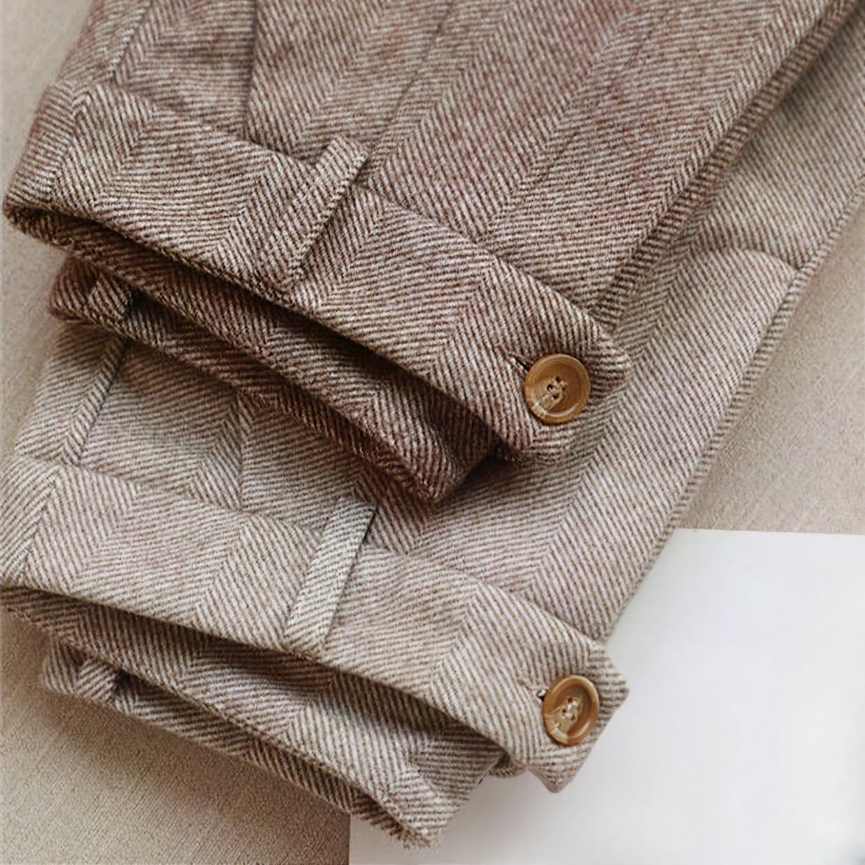 Detail of button fastening and waistband on men's herringbone pleated trousers