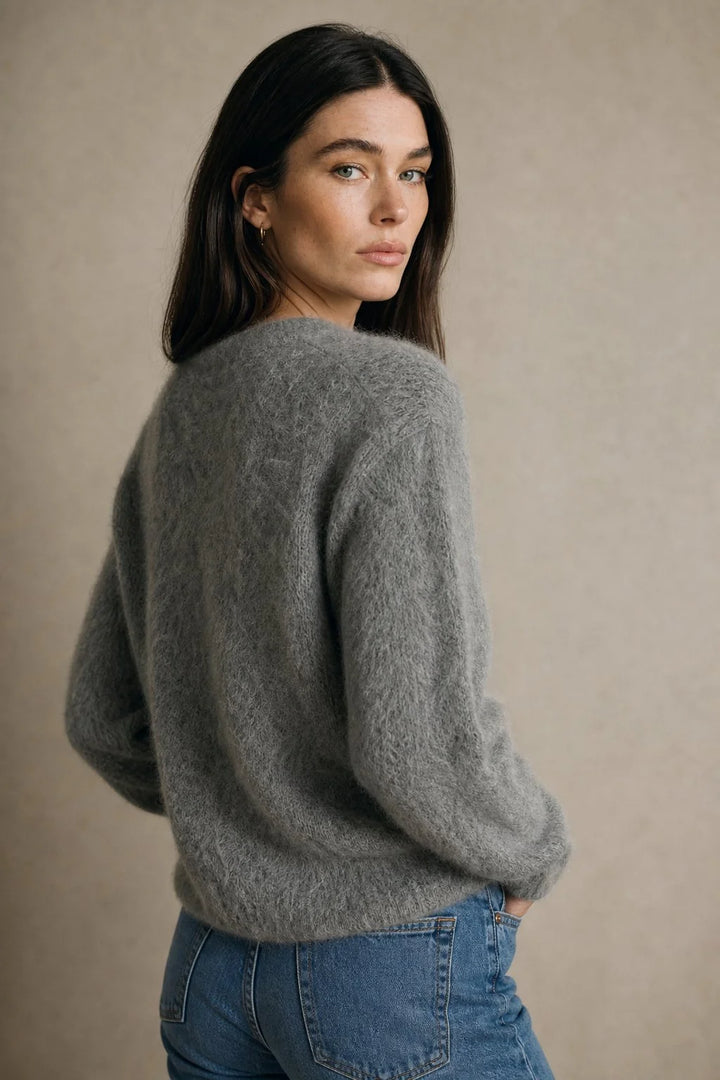 Woman layering cashmere cardigan over camisole for effortless casual style
