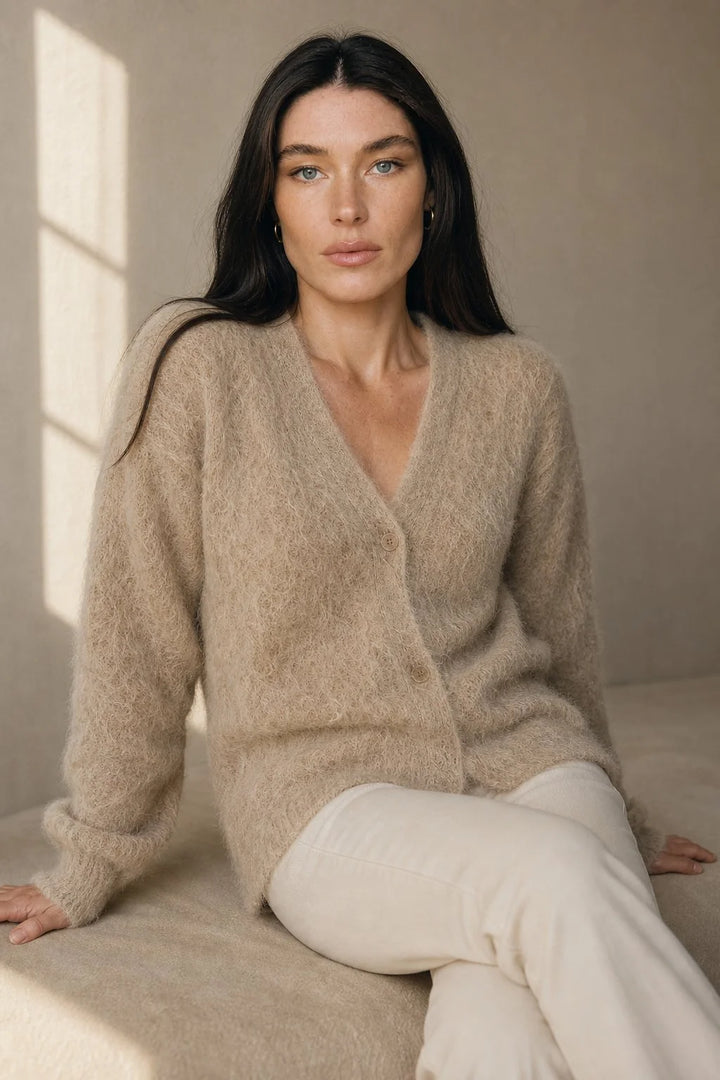 Woman wearing cream cashmere cardigan with hands in pockets showing relaxed fit